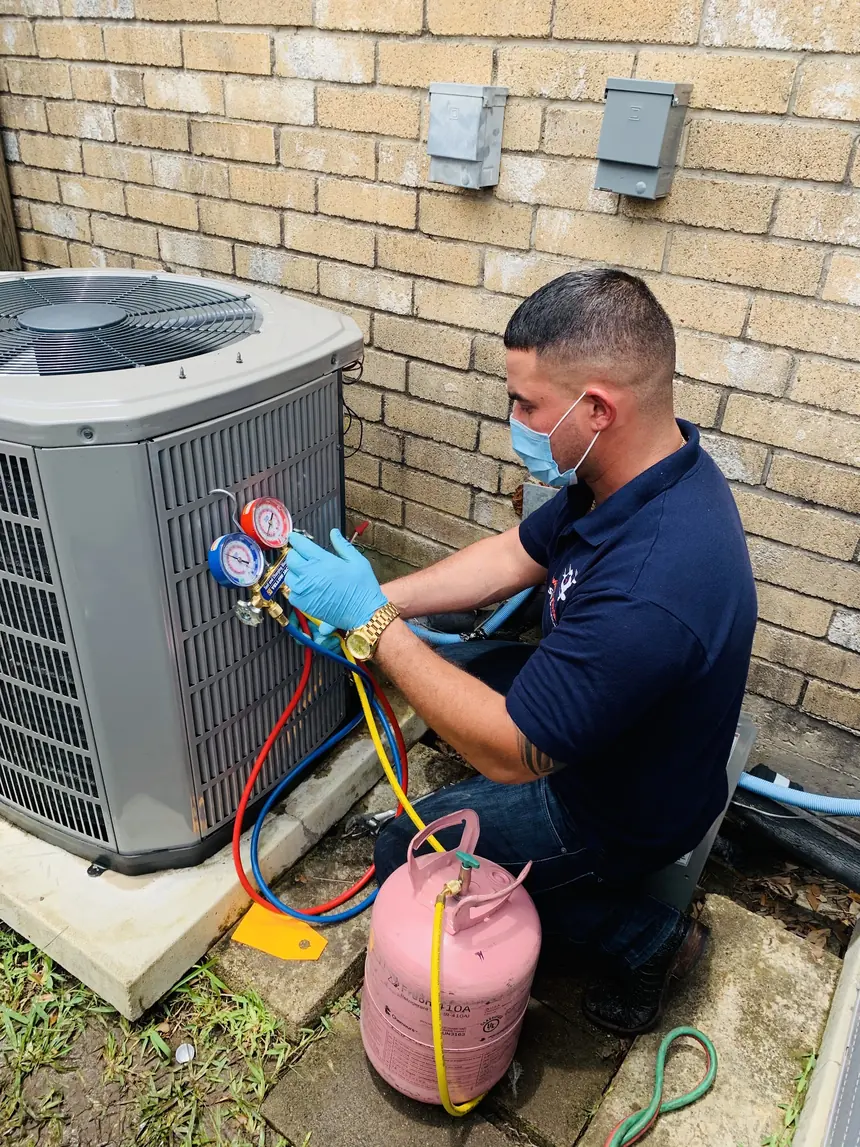 A technician charging an outdoor condenser with manifold gauges