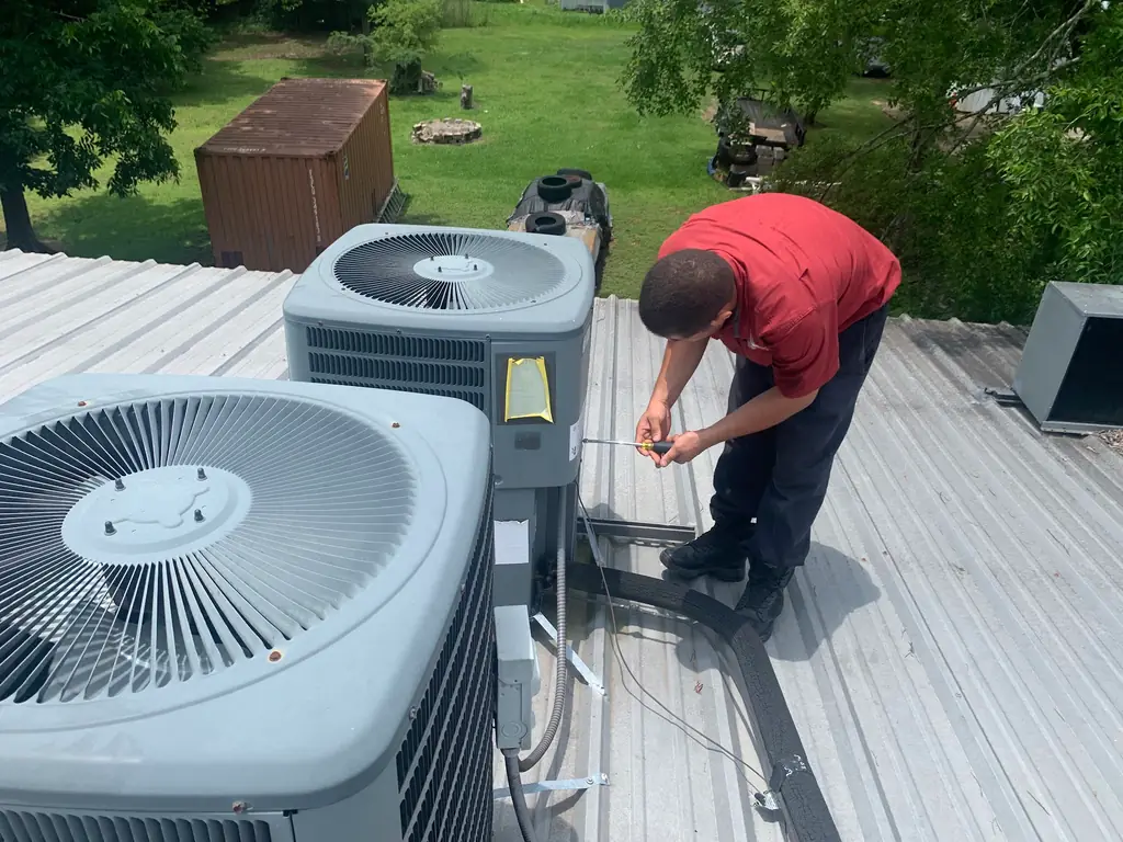 Two condensers installed on a metal roof, a technician working beside them